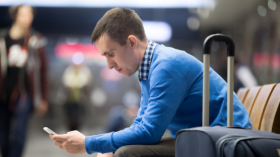 man on phone in airport with suitcase